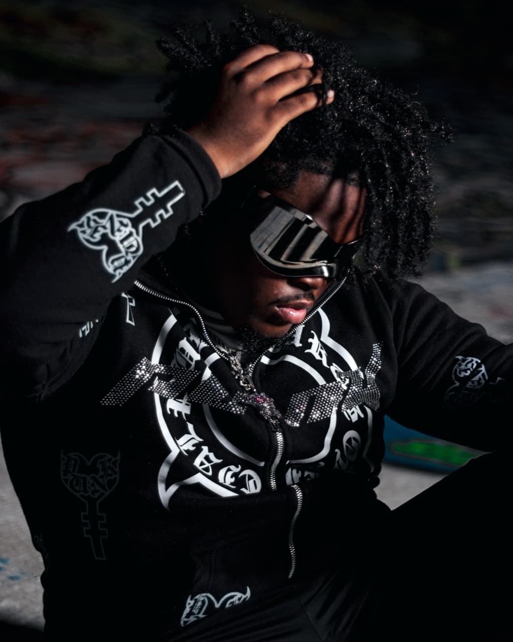 Low-key streetwear portrait with reflective goggles and black apparel