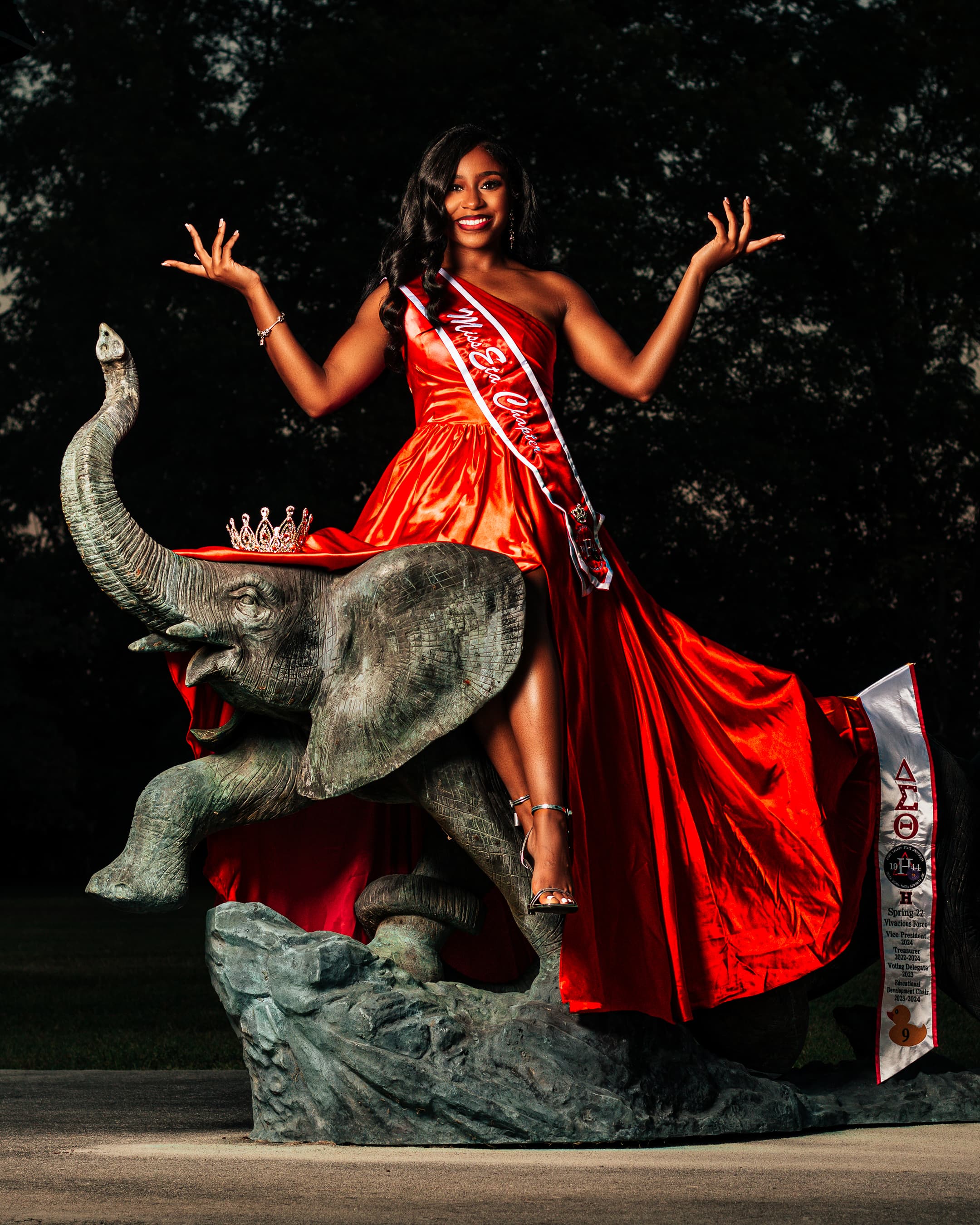 Graduation portrait in a red dress on a sculptural elephant setting